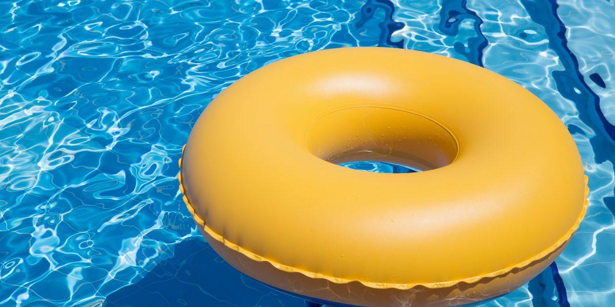 Hinchable en forma de donut de color amarillo flotando en el agua de una piscina