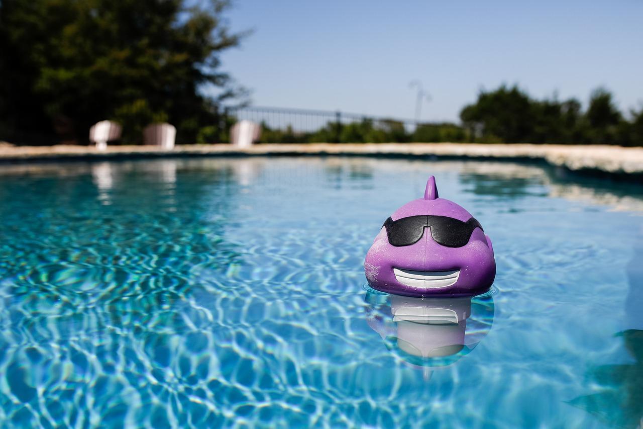 Juguete de agua de color lila sonriendo en una piscina mientras se encuentra flotando