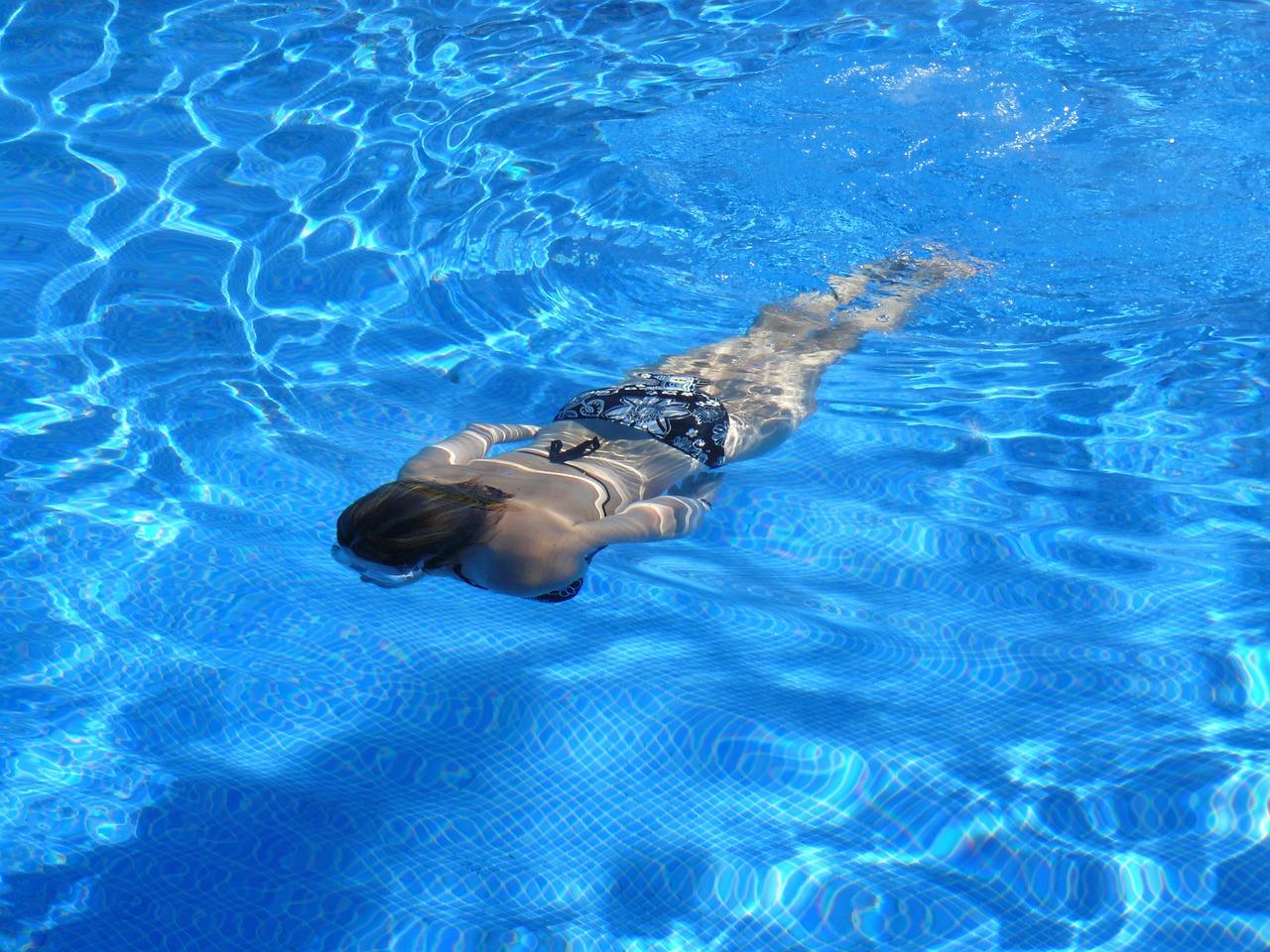 Chica nadando por una piscina mientras desconecta y se relaja